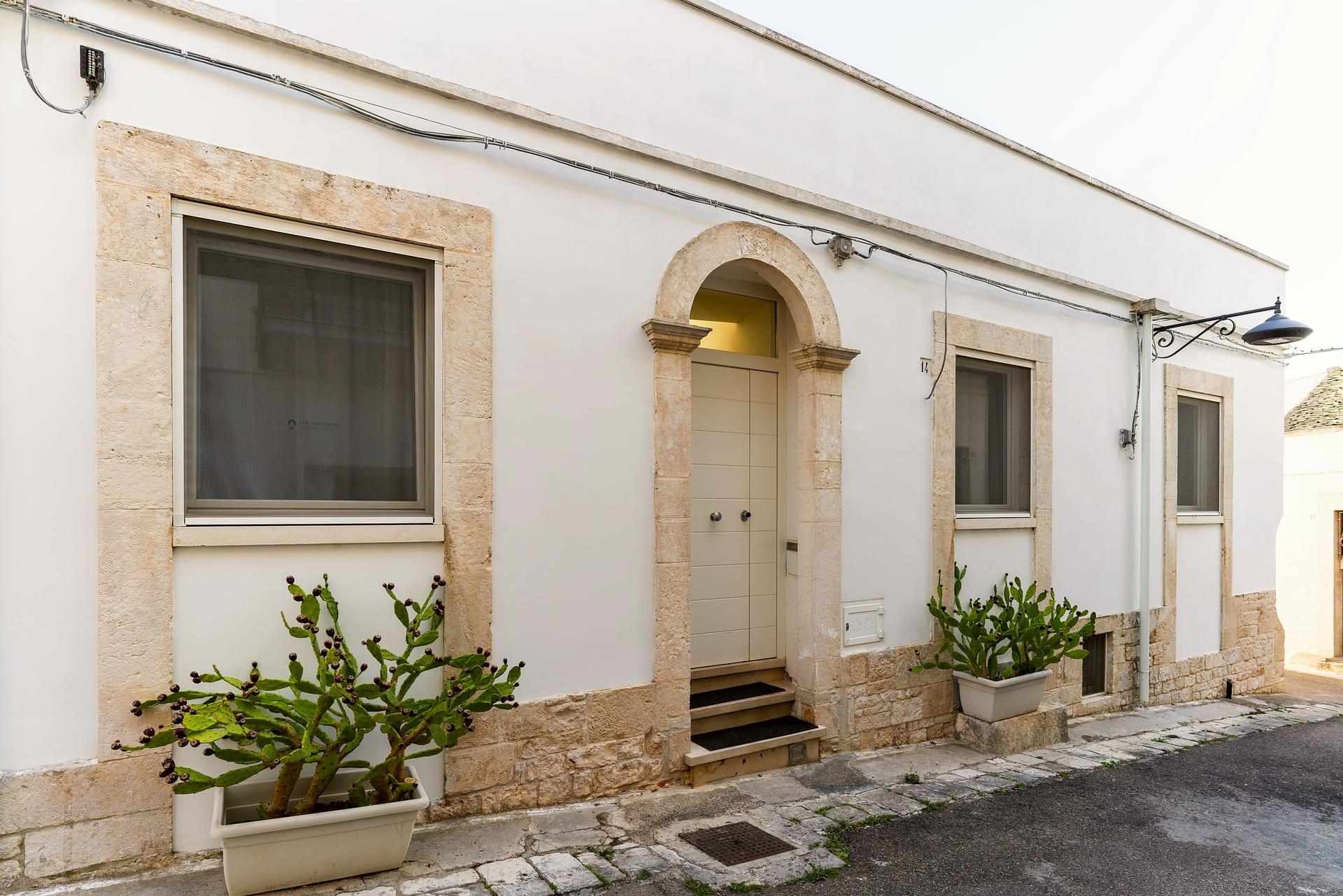 Caminetto — die weiße Fassade mit dem steinernen Bogenportal und Kaktusfeigen in Töpfen