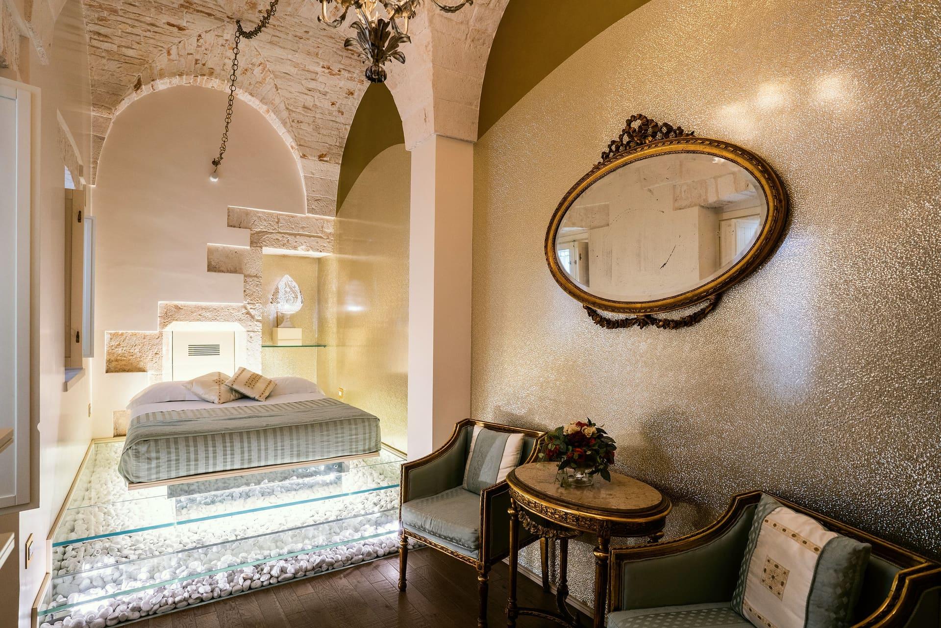 Foresteria — das ganze Zimmer, vom Bett auf dem Glasboden bis zum ovalen Spiegel an der goldenen Wand