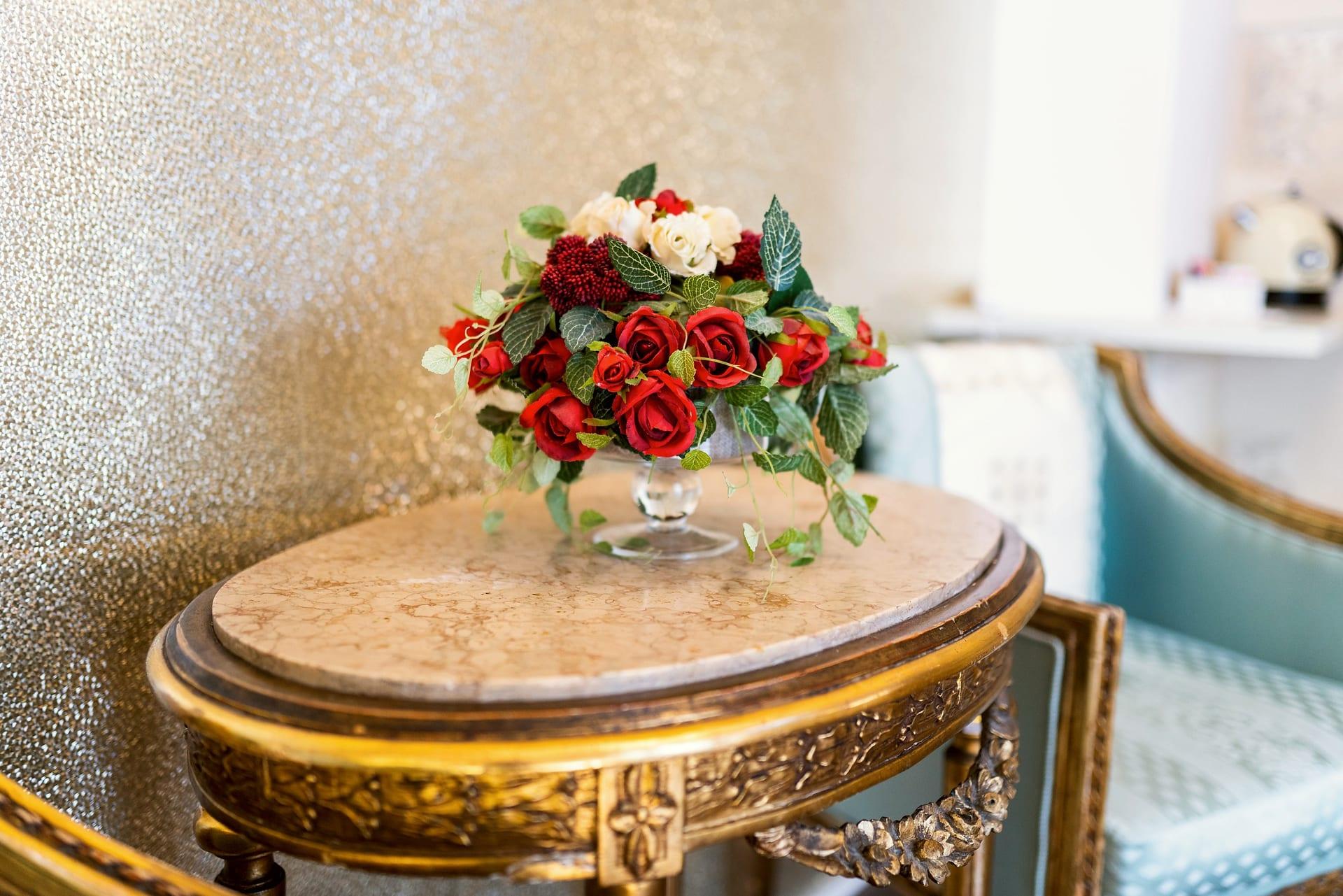 Foresteria — rote und weiße Rosen auf dem vergoldeten Tischchen mit Marmorplatte