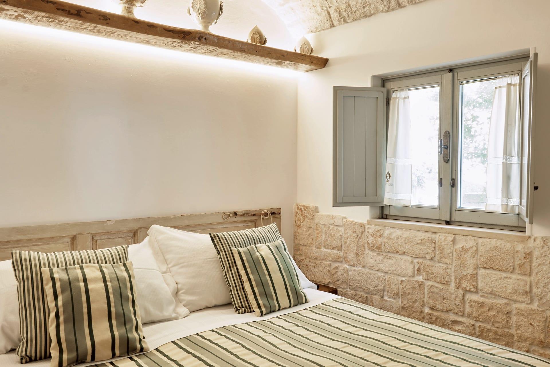 Suite Trullo — die beleuchtete Ablage mit Pumi aus Keramik, über den grün gestreiften Kissen