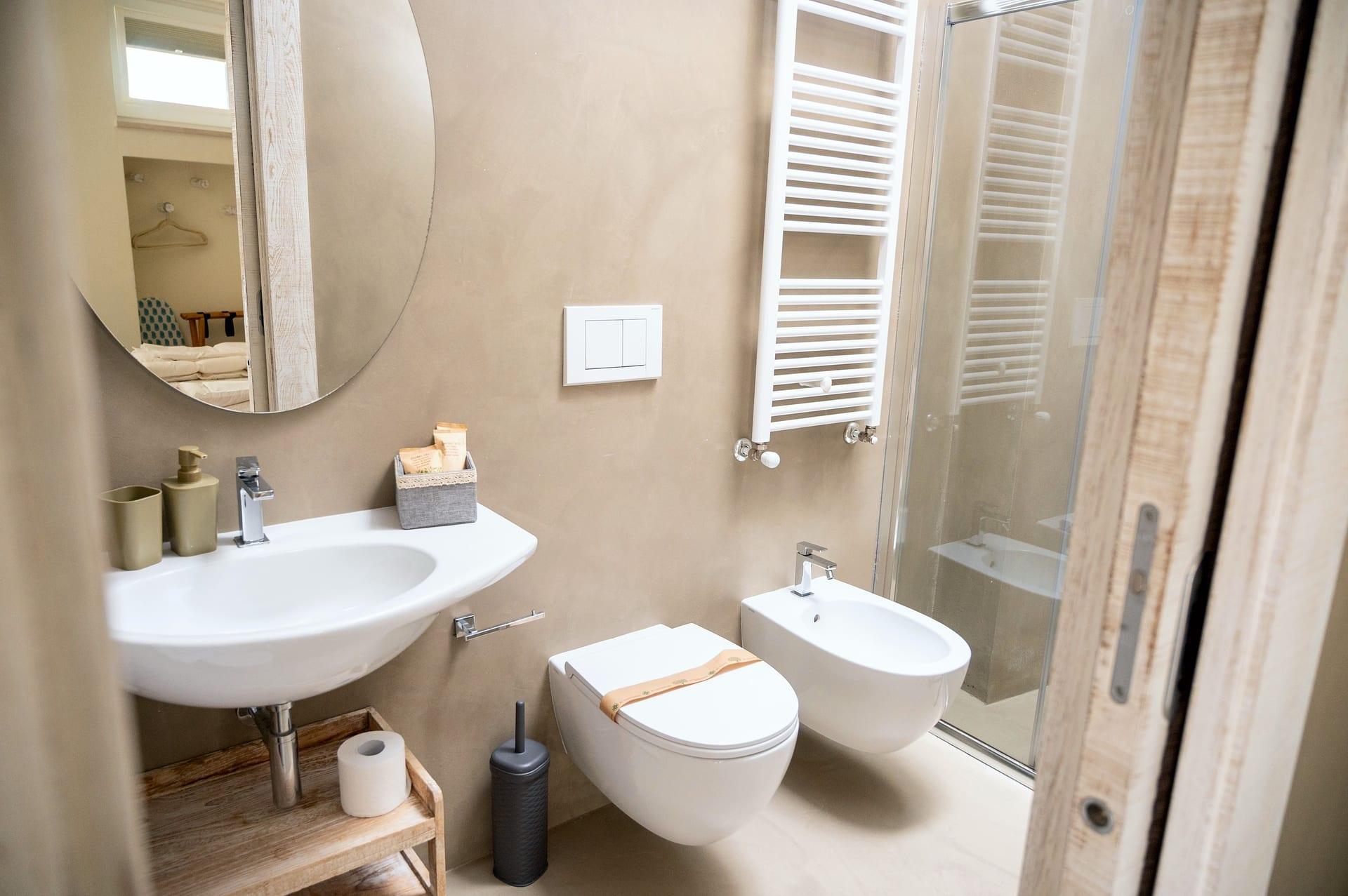 La Piccola — das Bad mit Glasdusche, weißem Handtuchheizkörper und ovalem Spiegel