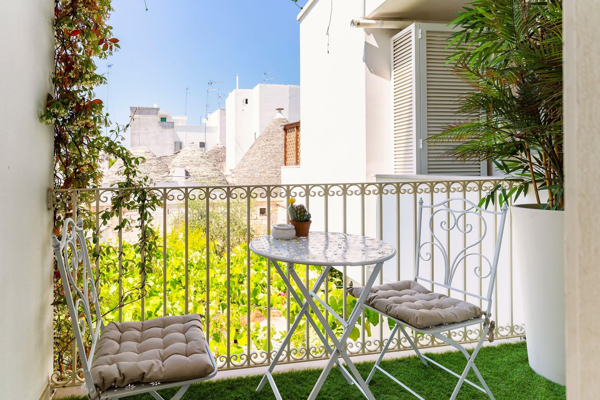 Nobile Deluxe — der kleine Balkon mit Tischchen und Stühlen aus weißem Eisen, mit Blick auf die Kegeldächer der Trulli