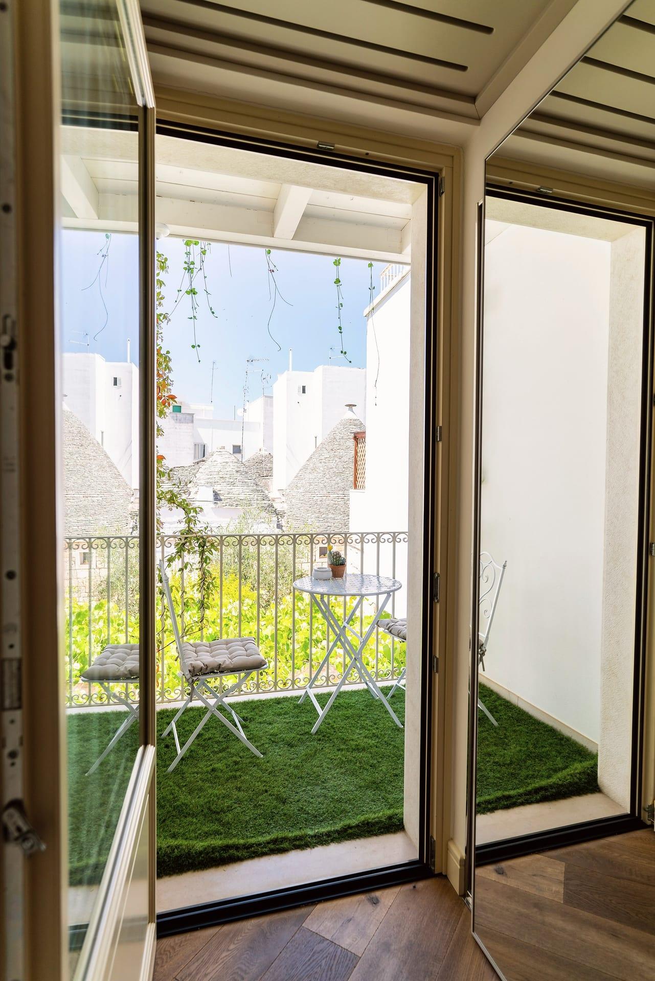 Nobile Deluxe — die offene Balkontür zum kleinen Balkon mit Kunstrasen, gegenüber den Kegeldächern der Trulli