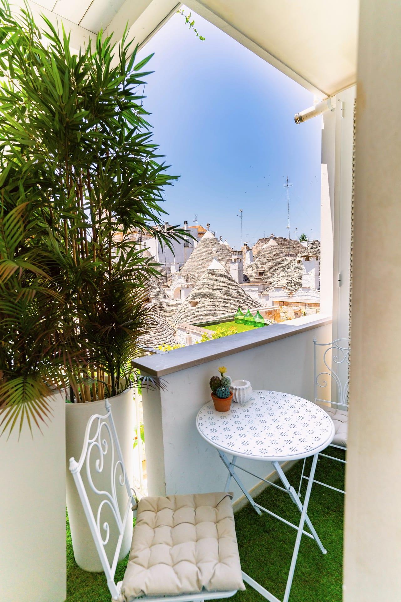 Nobile Suite — der kleine Balkon mit Palme im Topf und blau gemustertem Tischchen, offen zu den Trulli