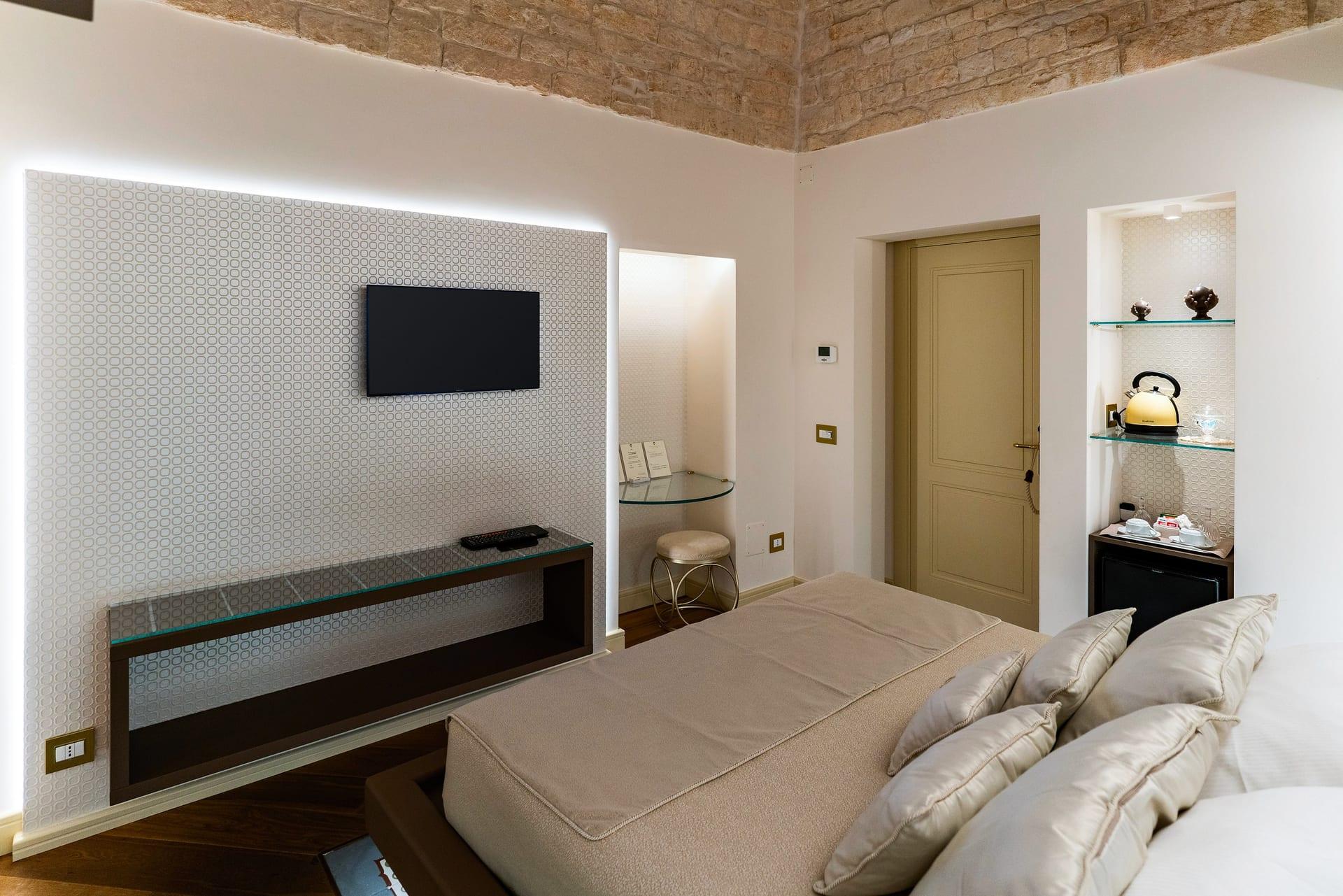 Nobile Suite — der Fernseher an der Reliefwand und die Nische mit Hocker, vom Bett aus gesehen