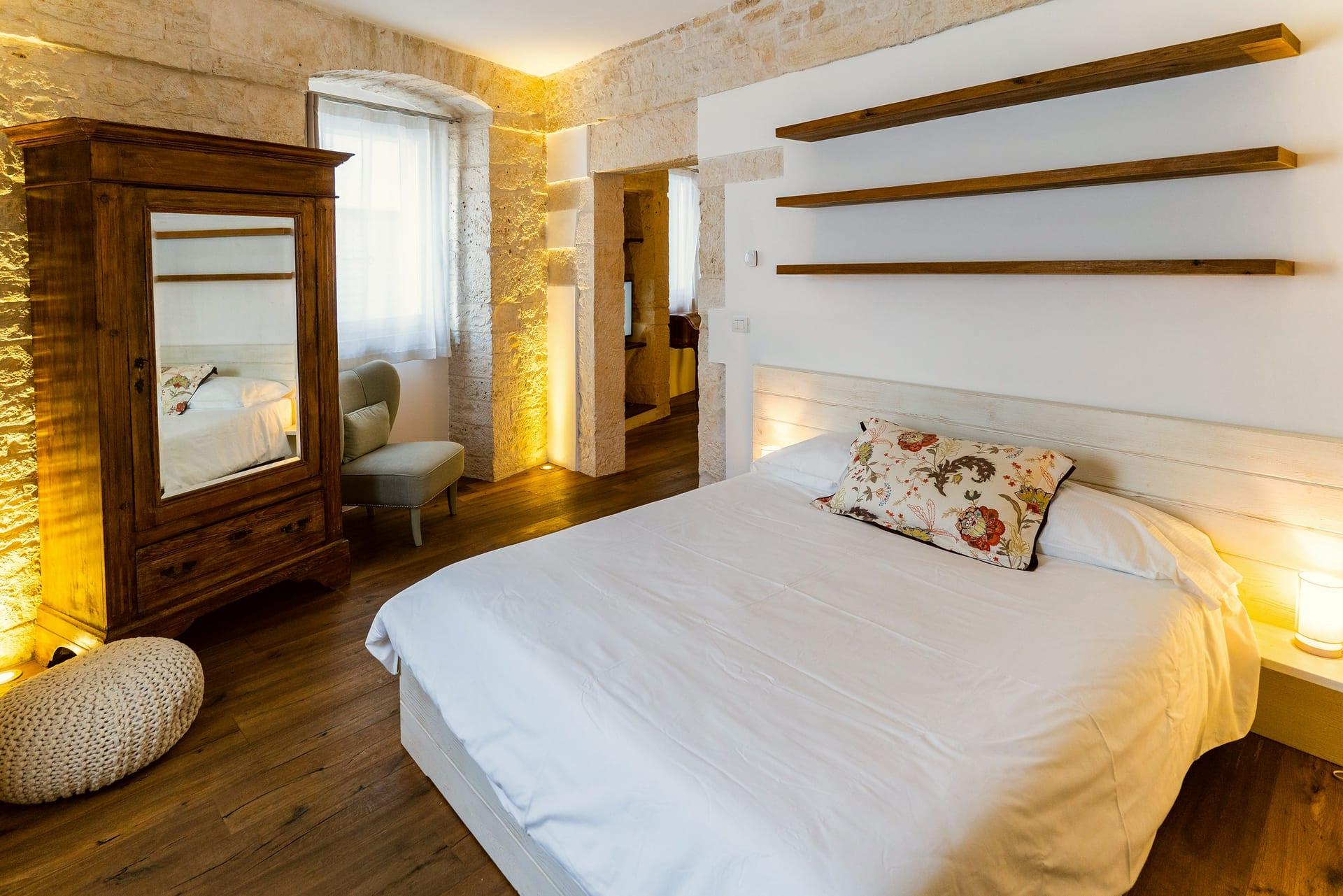 Pietra — la cama con el cojín de flores y el cabecero de madera decapada