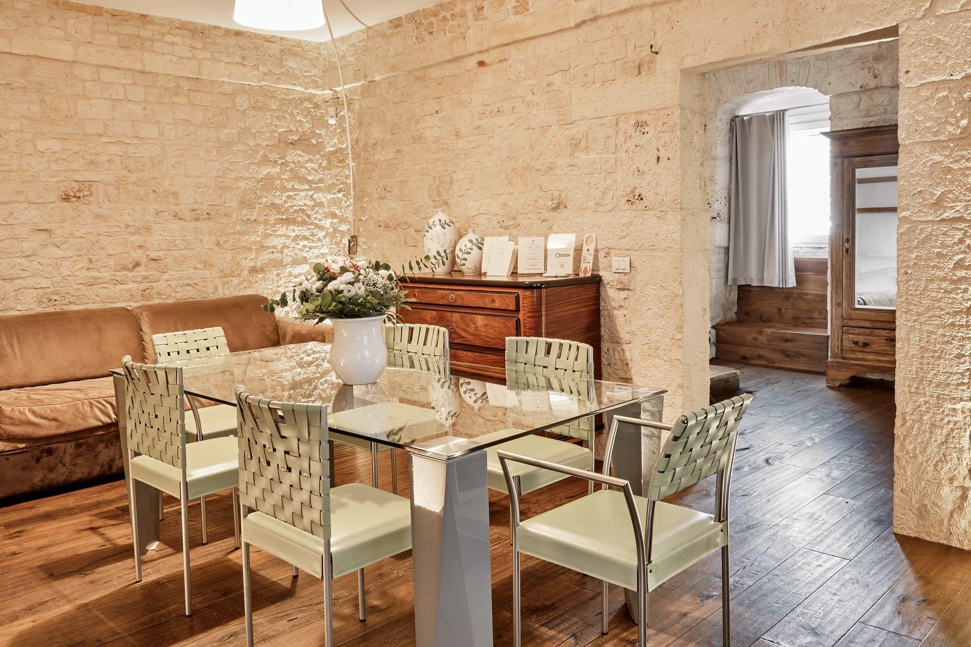Pietra — la mesa de cristal con las sillas trenzadas, el sofá color cuero y la cómoda