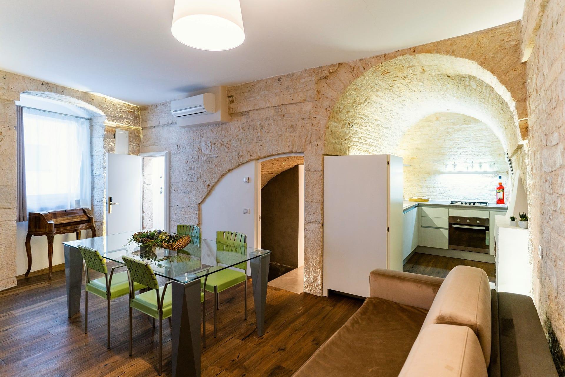 Pietra — el comedor y la cocina bajo el gran arco de piedra, vistos desde el sofá