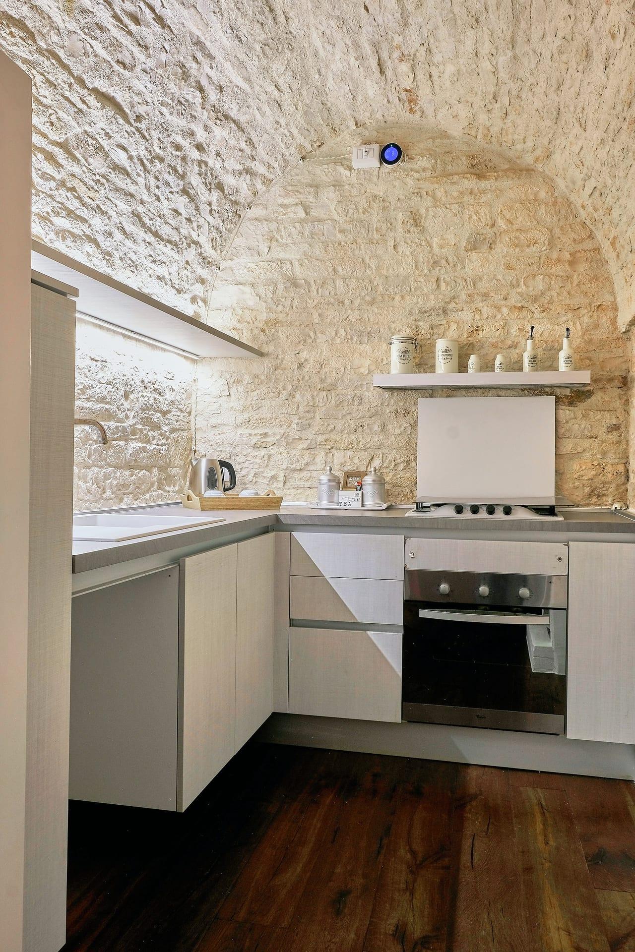 Pietra — el horno y la placa de cocción, con el estante de los tarros en la pared de piedra