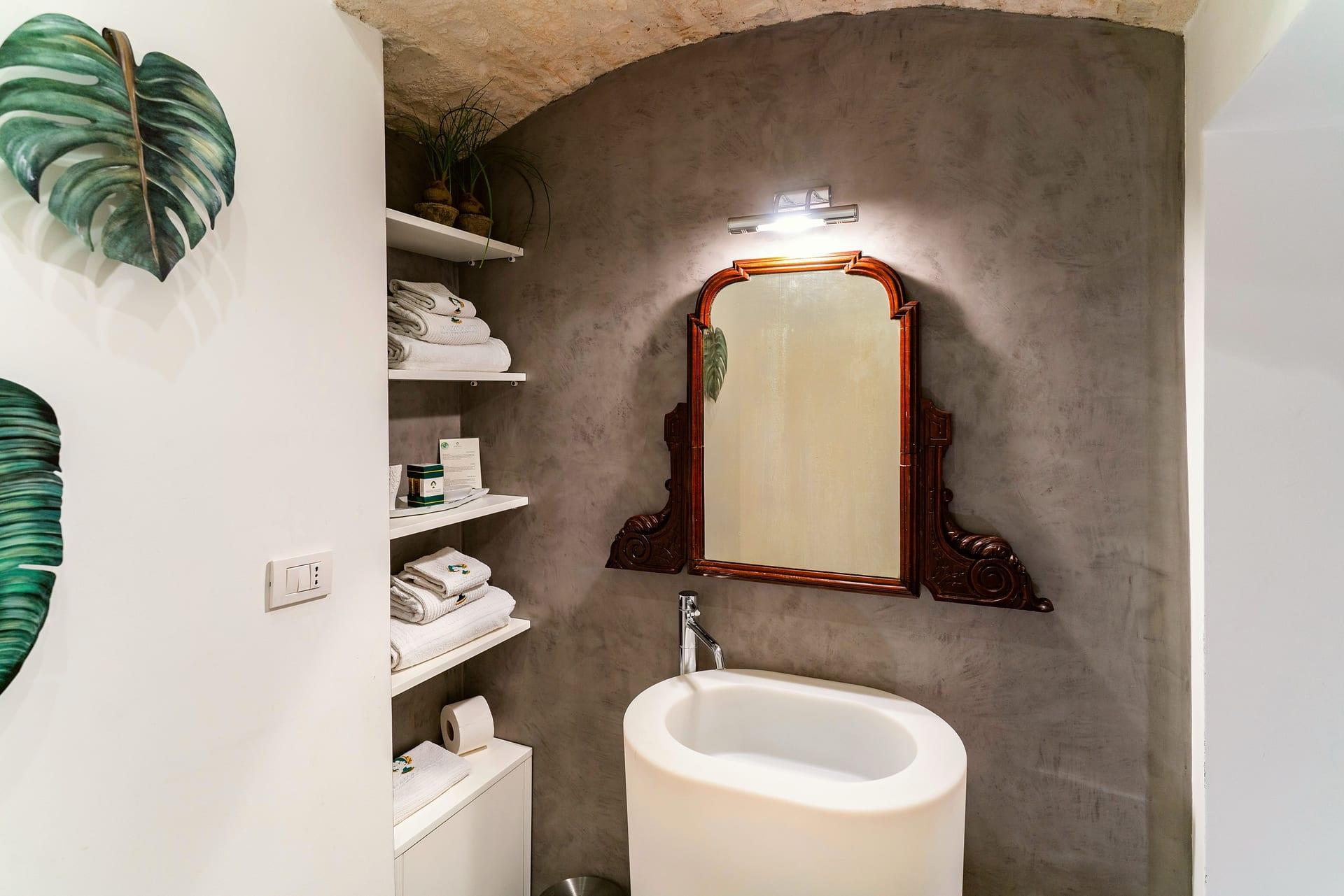 Pietra — el lavabo de columna blanco bajo el espejo de madera tallada