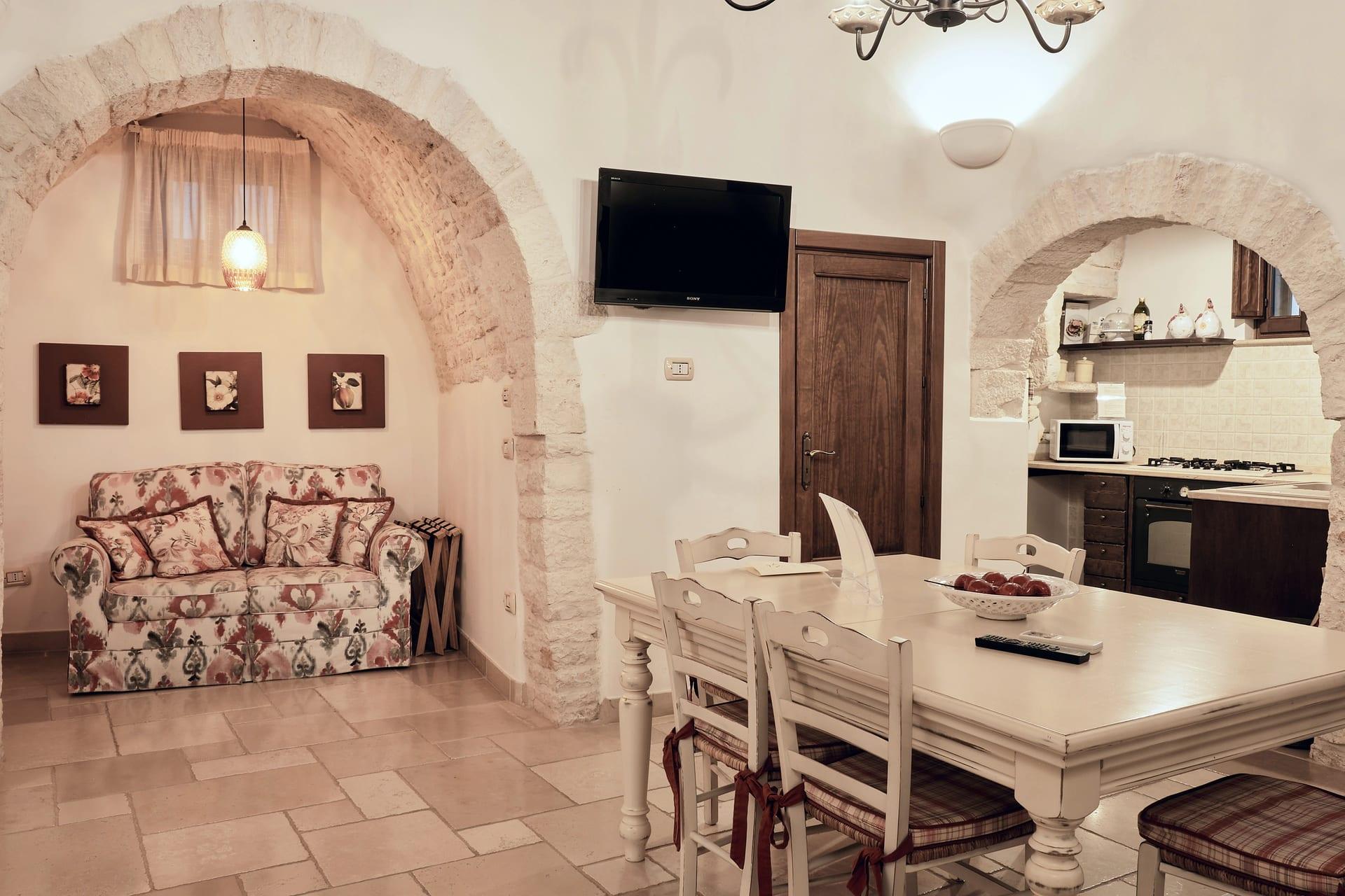 Trullo Maestro — das geblümte Sofa, die drei kleinen Bilder und der Tisch mit der Schale mit Äpfeln