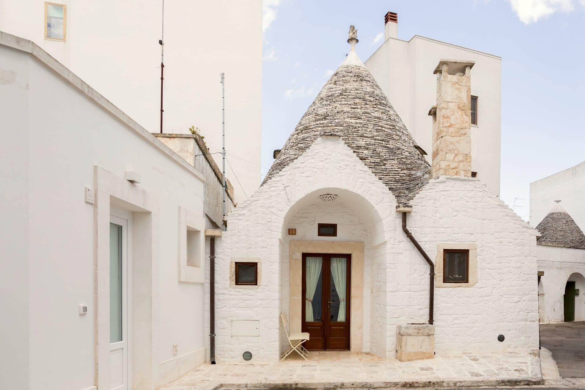 Trullo Maestro — die weiß gekalkte Fassade des Trullo, mit dem Steinkegel und der Tür unter dem Bogen