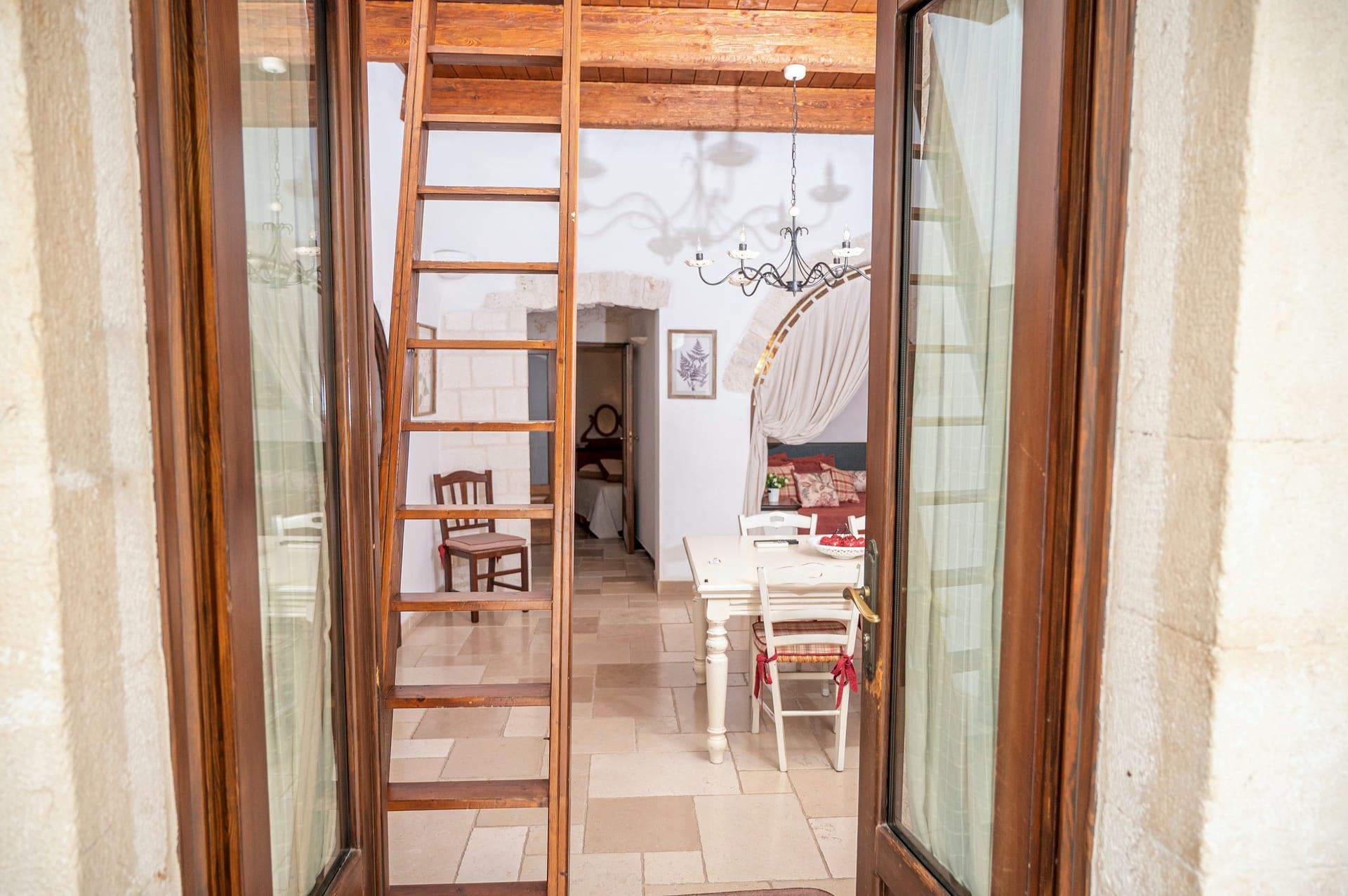 Trullo Maestro — die Eingangstür, offen zum Wohnraum, mit der Sprossenleiter und dem Tisch