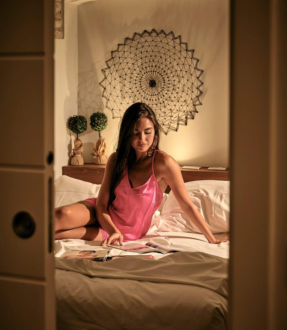 Caminetto — ein Gast blättert auf dem Bett in einer Zeitschrift, von der Tür aus gesehen