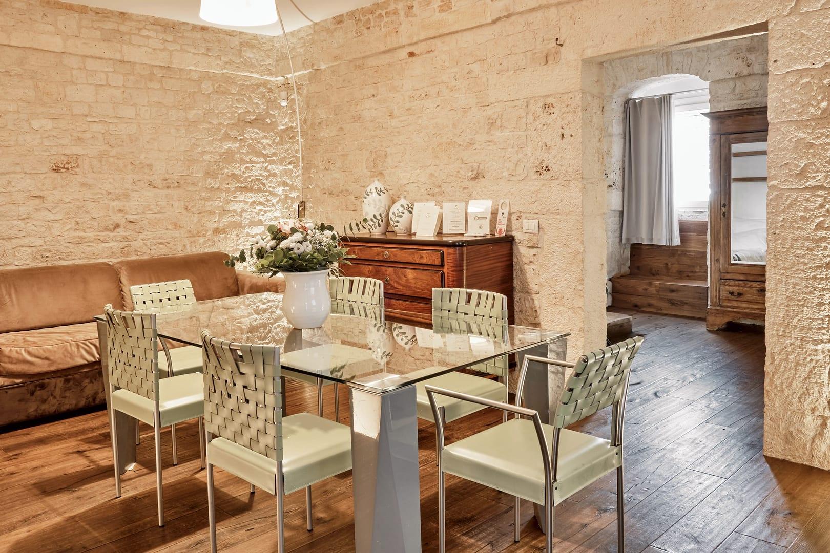 Pietra — el salón con la mesa de cristal y las paredes de piedra vista