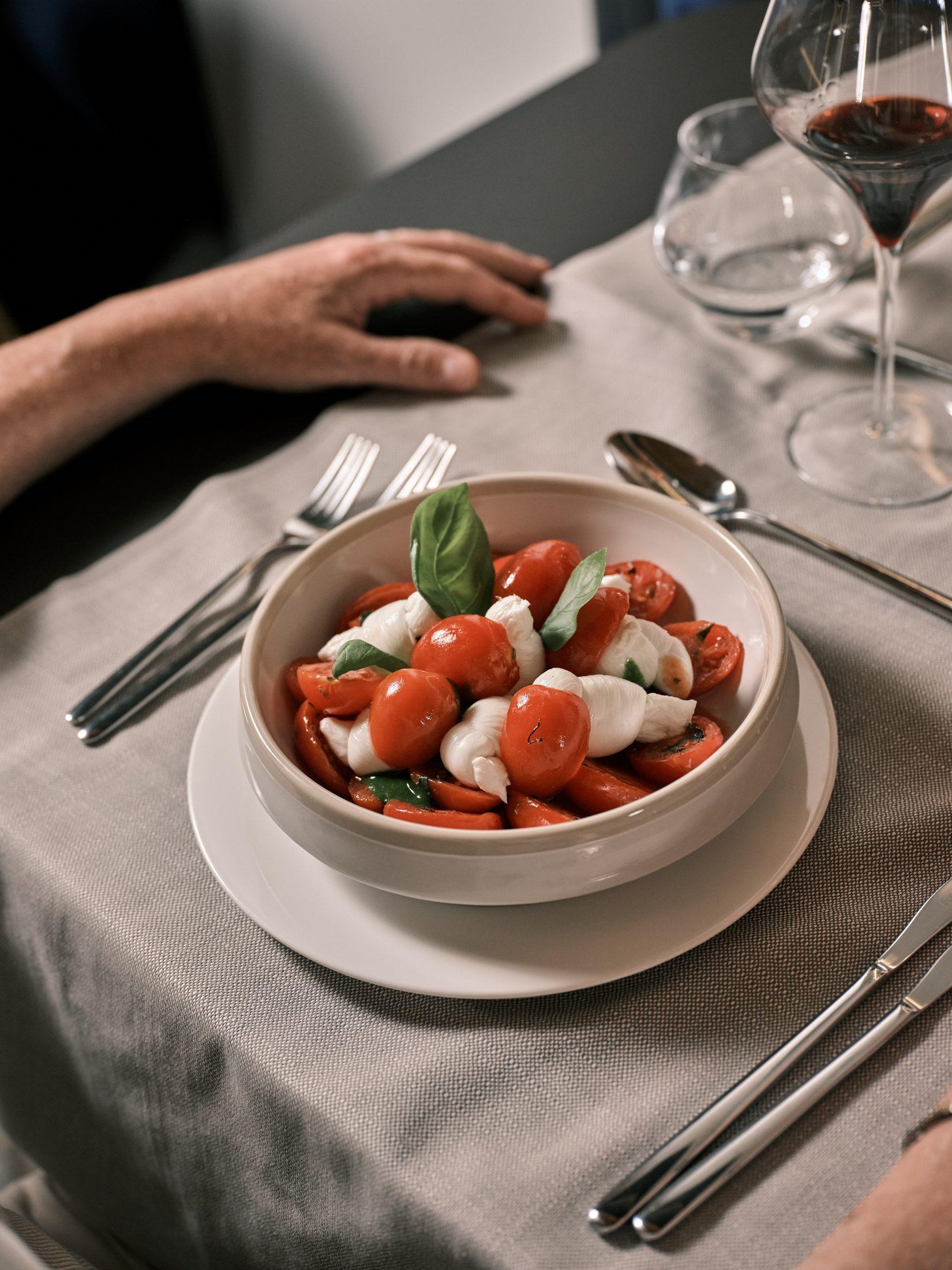 Kirschtomaten, Mozzarella und Basilikum in einer Schale, auf einem Tisch im NOS