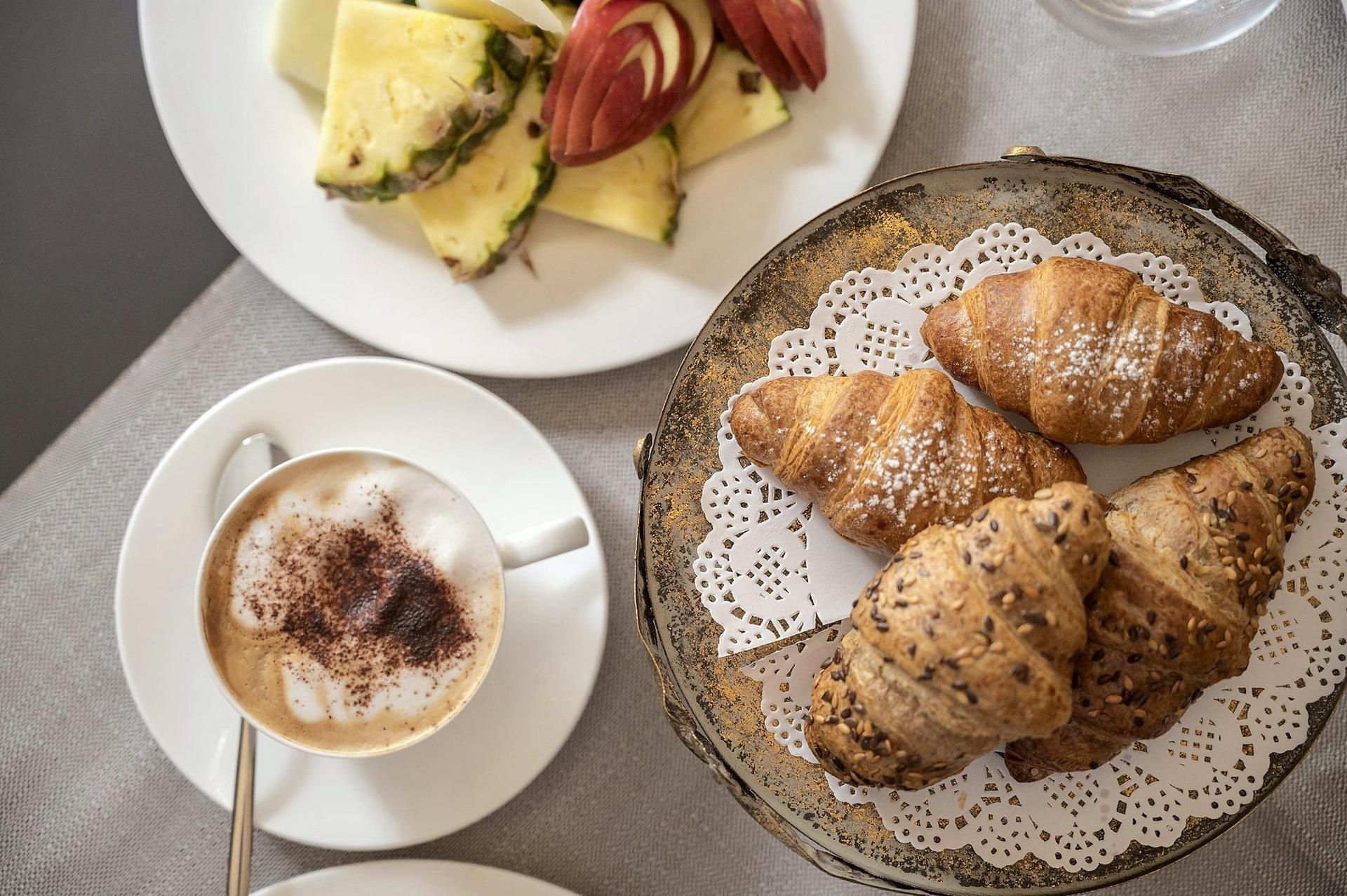 El desayuno en la mesa: capuchino, fruta fresca y cornetti
