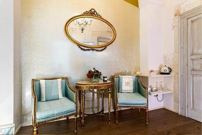 Ein kleiner Salon im Palazzo: der vergoldete ovale Spiegel, zwei hellblaue Sessel und ein Tischchen mit Rosen