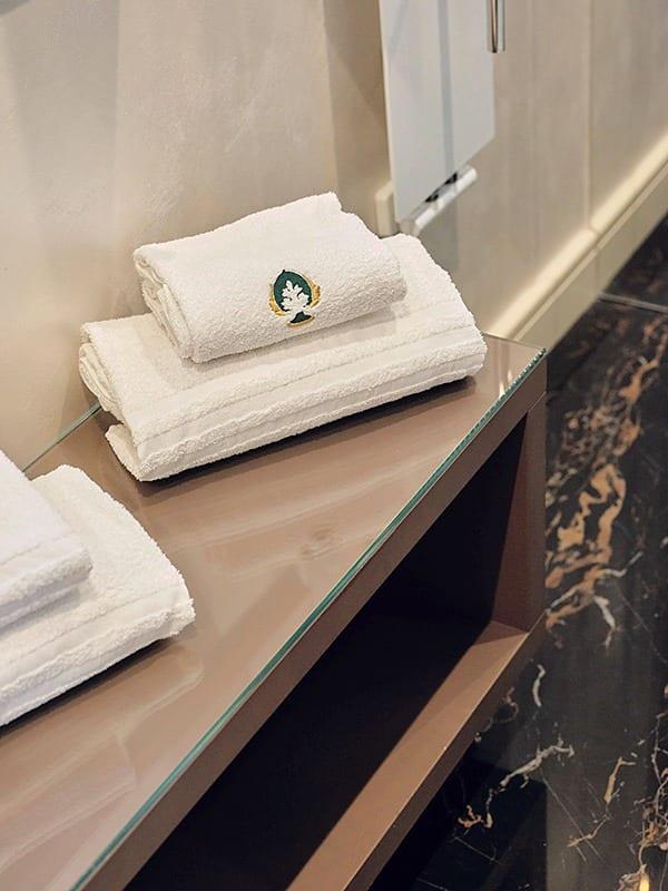 Handdoeken met de geborduurde pumo van Palazzo Scotto, in de badkamer van een kamer