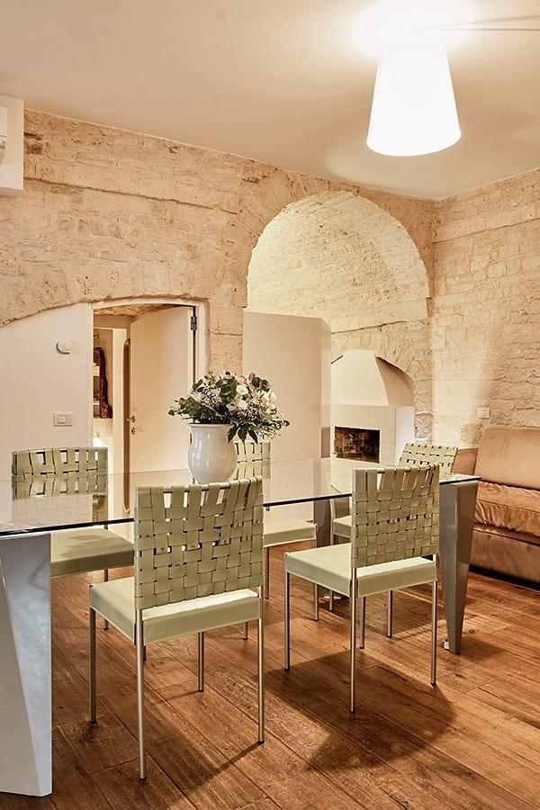 Pietra — la mesa de comedor frente a la chimenea, bajo el arco de piedra