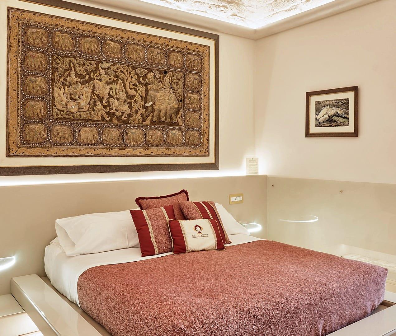 Nobile Deluxe — das Bett unter dem großen goldenen Wandteppich, mit der sichtbaren Steindecke