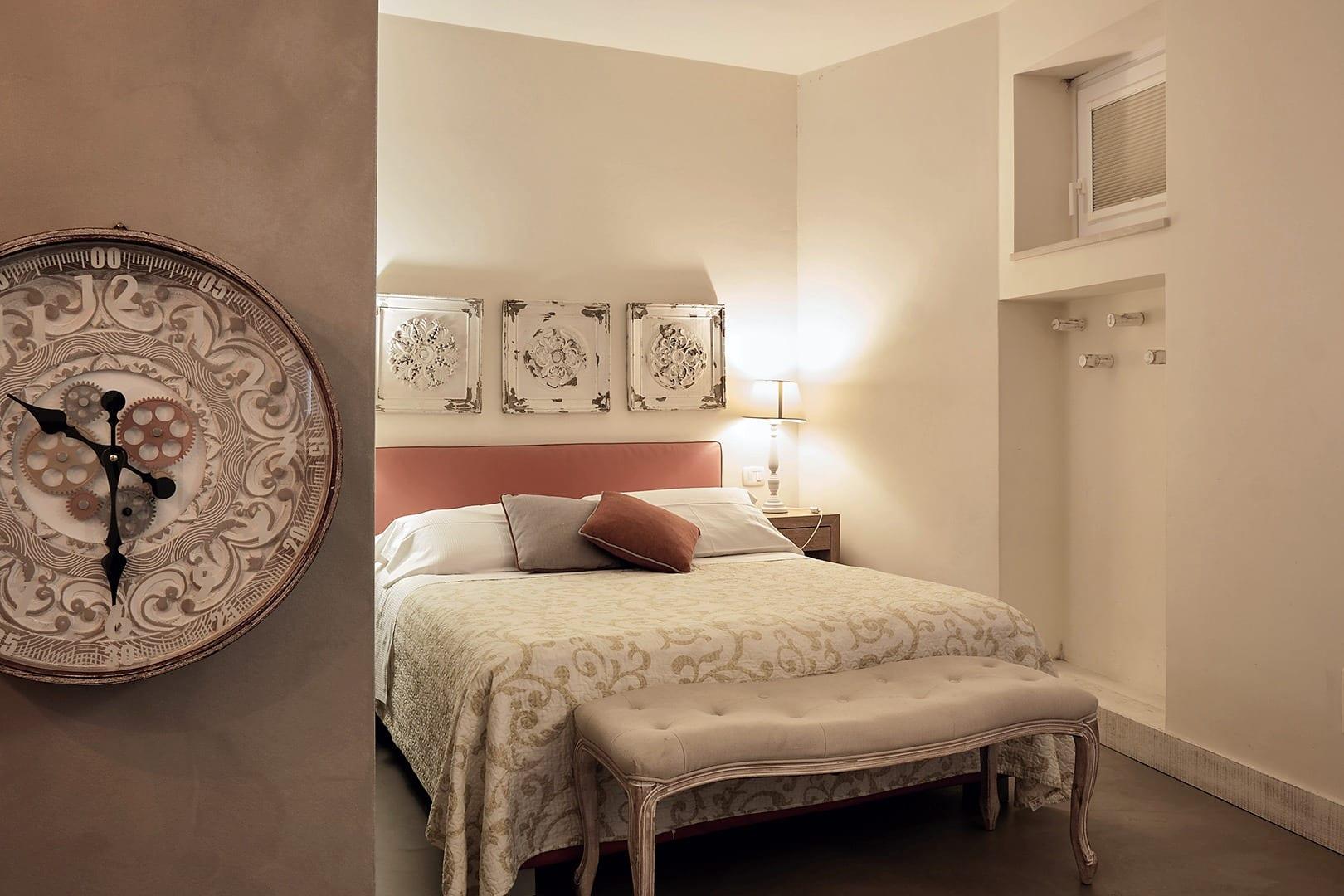 La Piccola — das Zimmer mit der großen Wanduhr und dem korallenroten Kopfteil