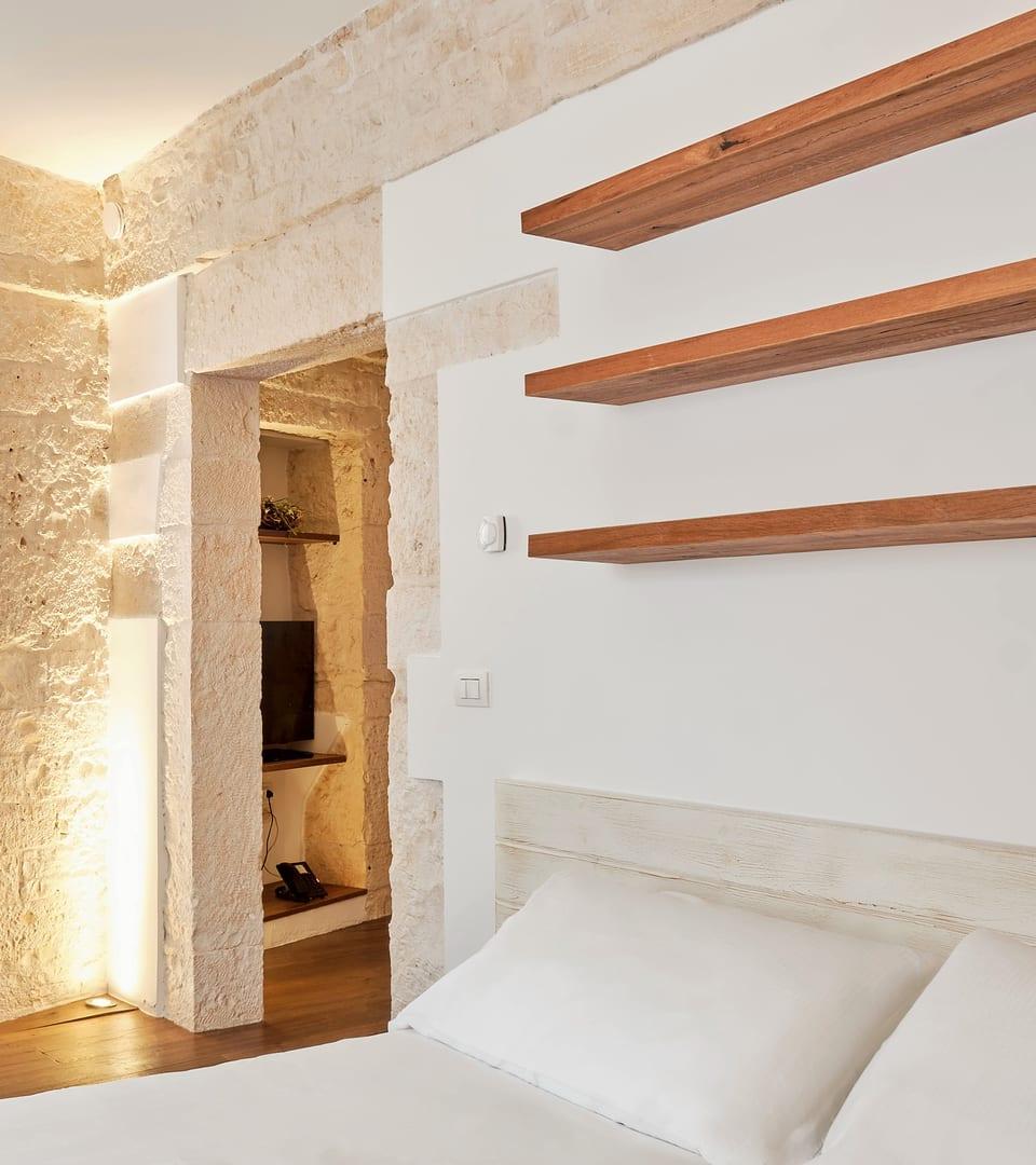 Pietra — la cama entre la pared de piedra vista y las estanterías de madera maciza