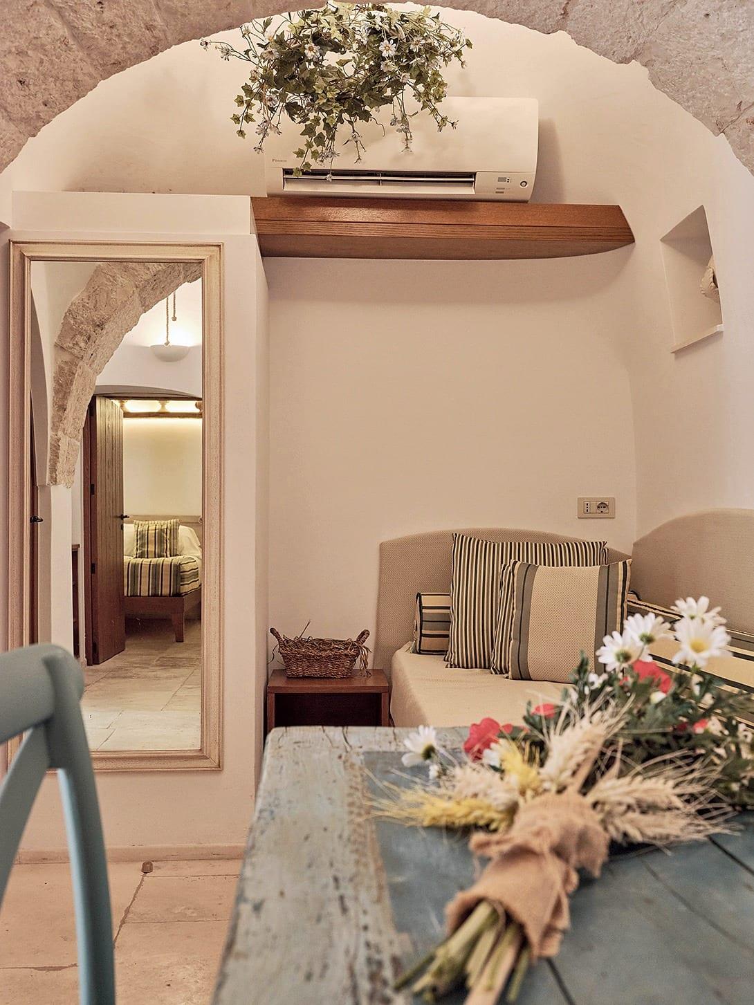 Suite Trullo — der Wohnbereich unter dem Steinbogen, mit dem Spiegel zum Schlafzimmer