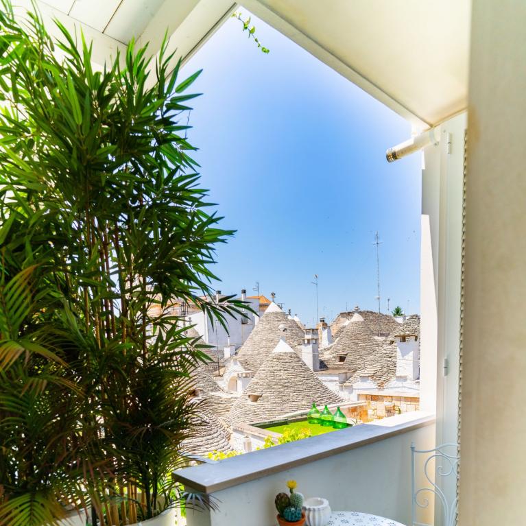 Balcone soleggiato, verde rigoglioso, vista sui trulli storici.