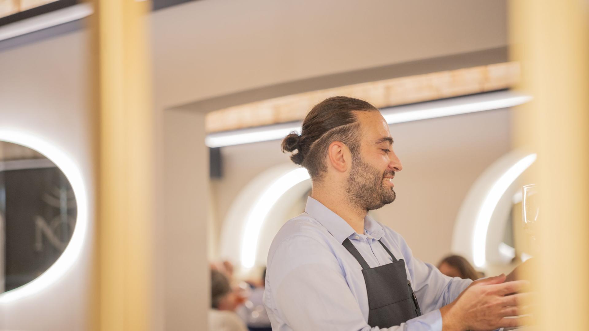 Smiling waiter in an elegant restaurant with soft lighting.