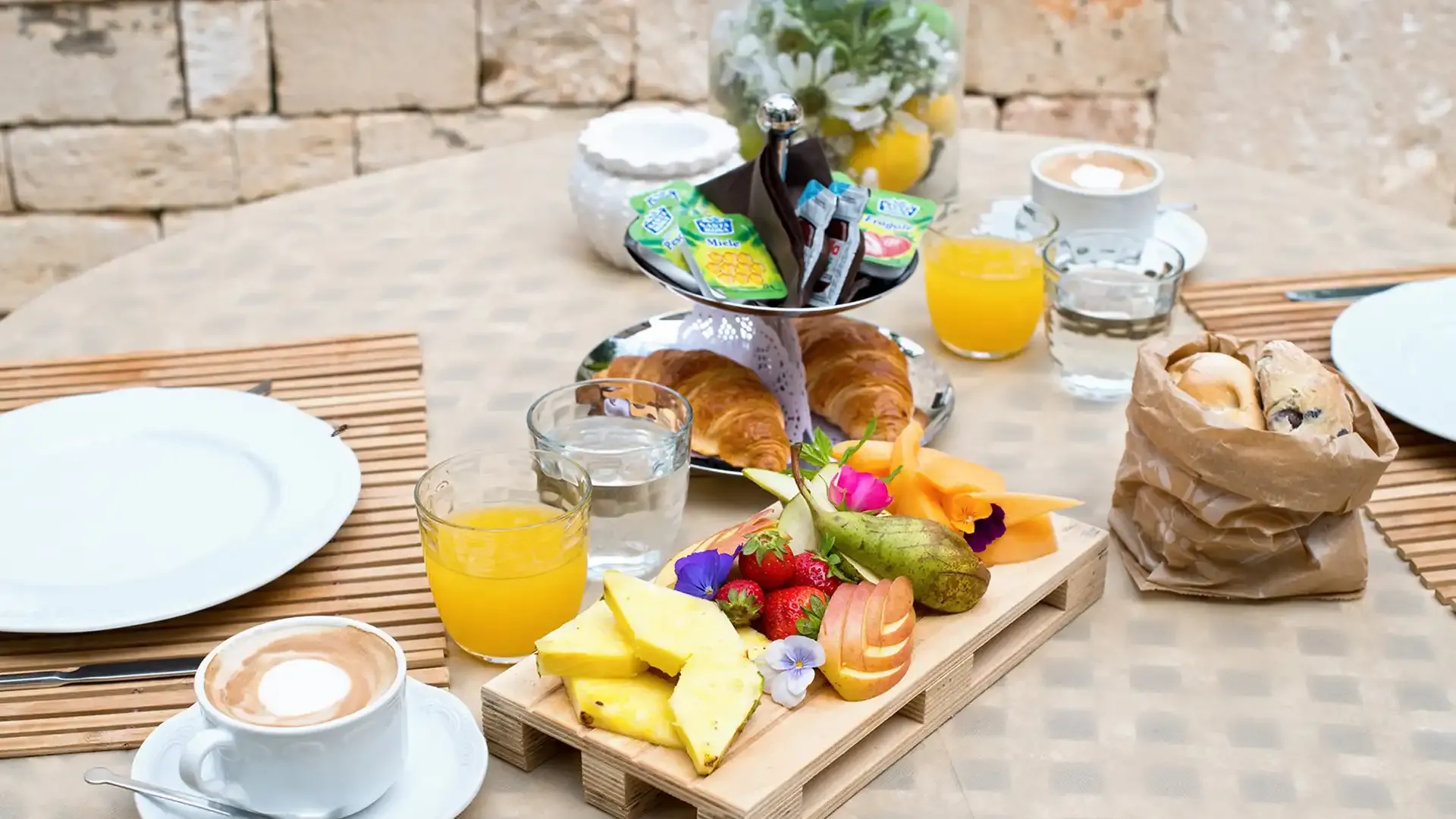 Breakfast with fresh fruit, croissants, orange juice, and cappuccino.