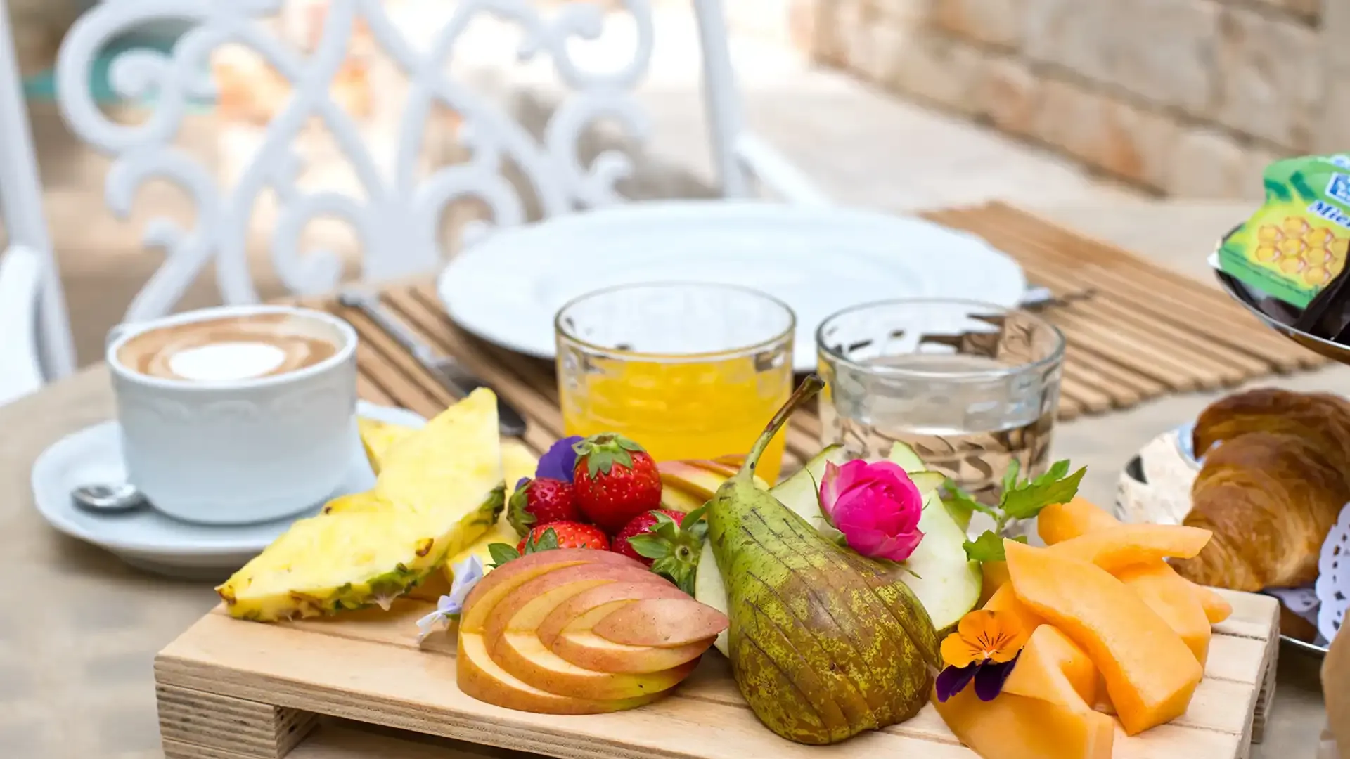 Breakfast with fresh fruit, juice, coffee, and croissant.