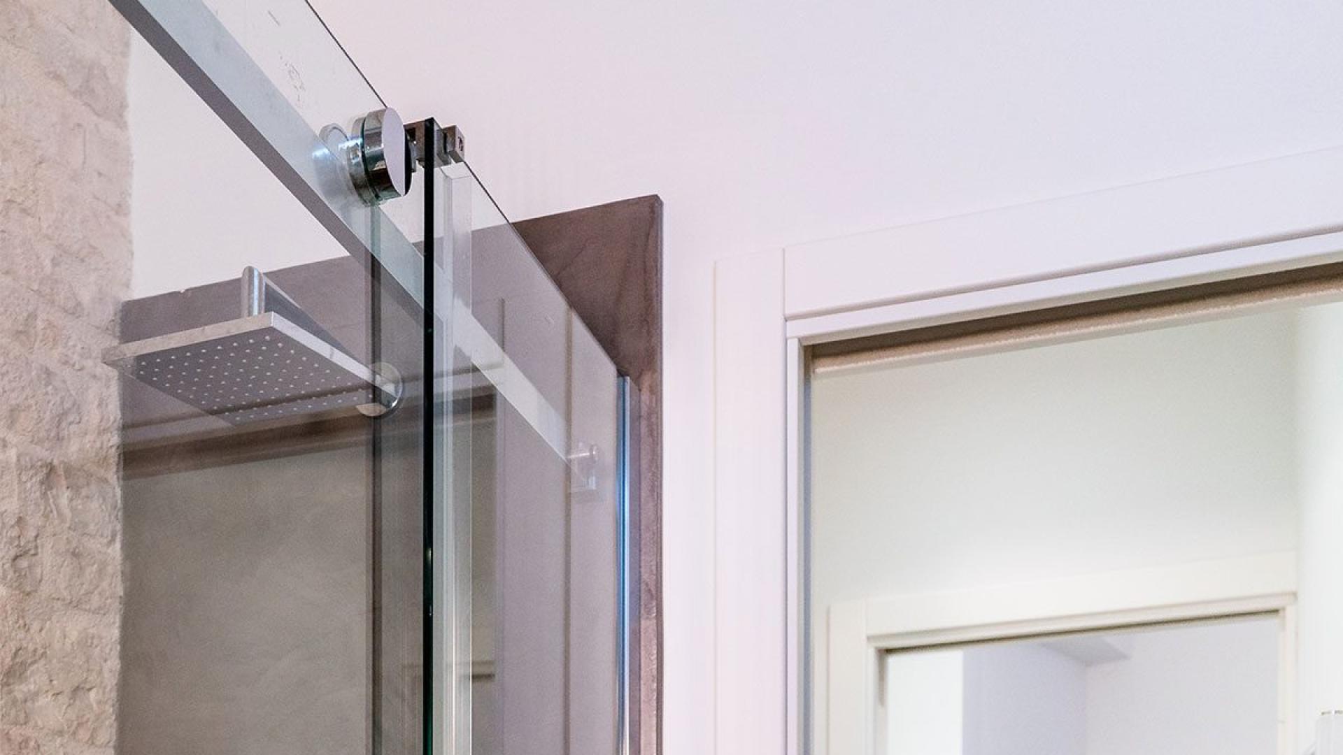 Bagno moderno con doccia in vetro e vista su salotto accogliente.