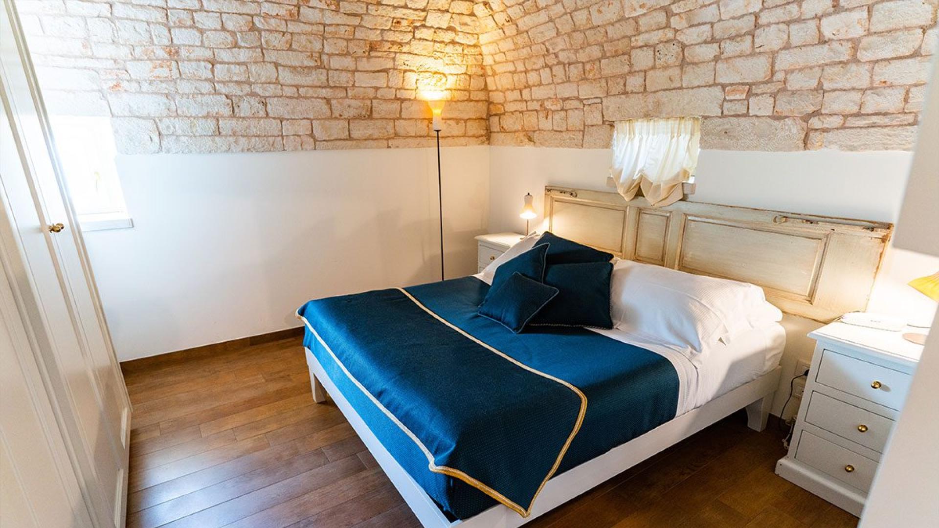 Camera accogliente con letto matrimoniale, pareti in pietra e pavimento in legno.