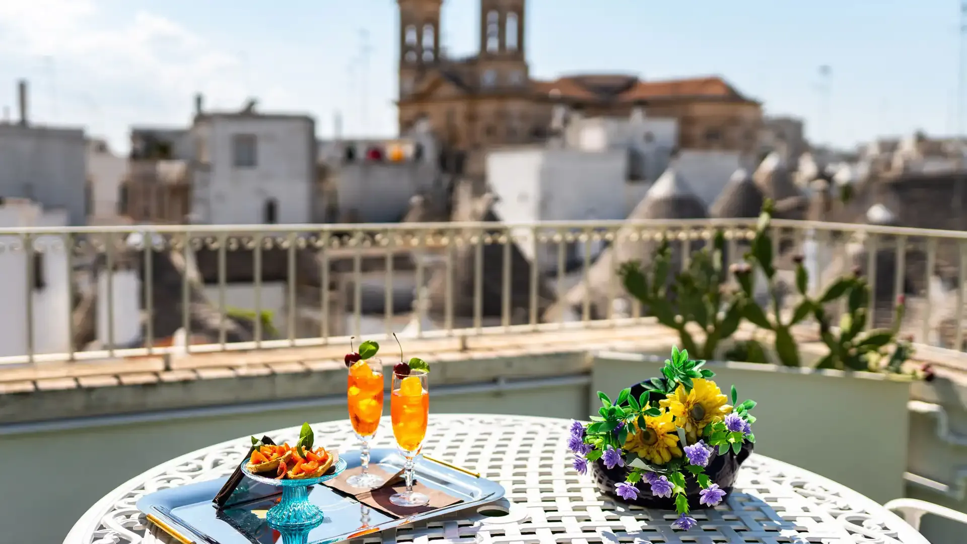 Tavolo con cocktail e snack su una terrazza con vista sulla città.