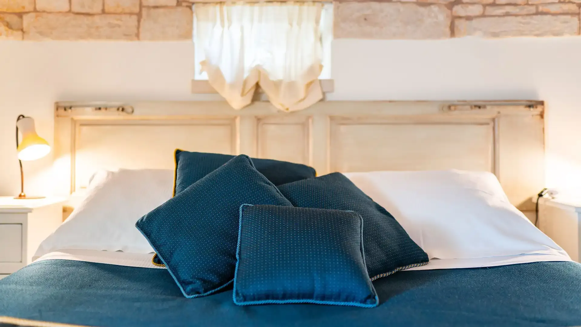 Letto con cuscini blu e copriletto in una stanza accogliente.