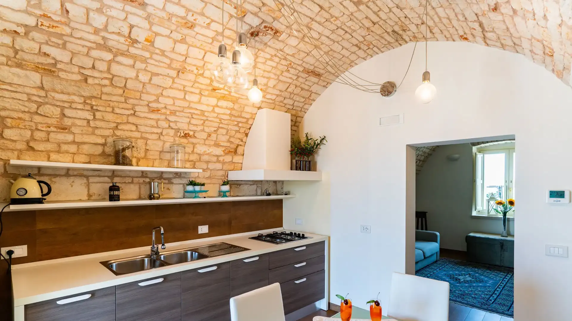 Cucina moderna con soffitto a volta in mattoni e tavolo apparecchiato.