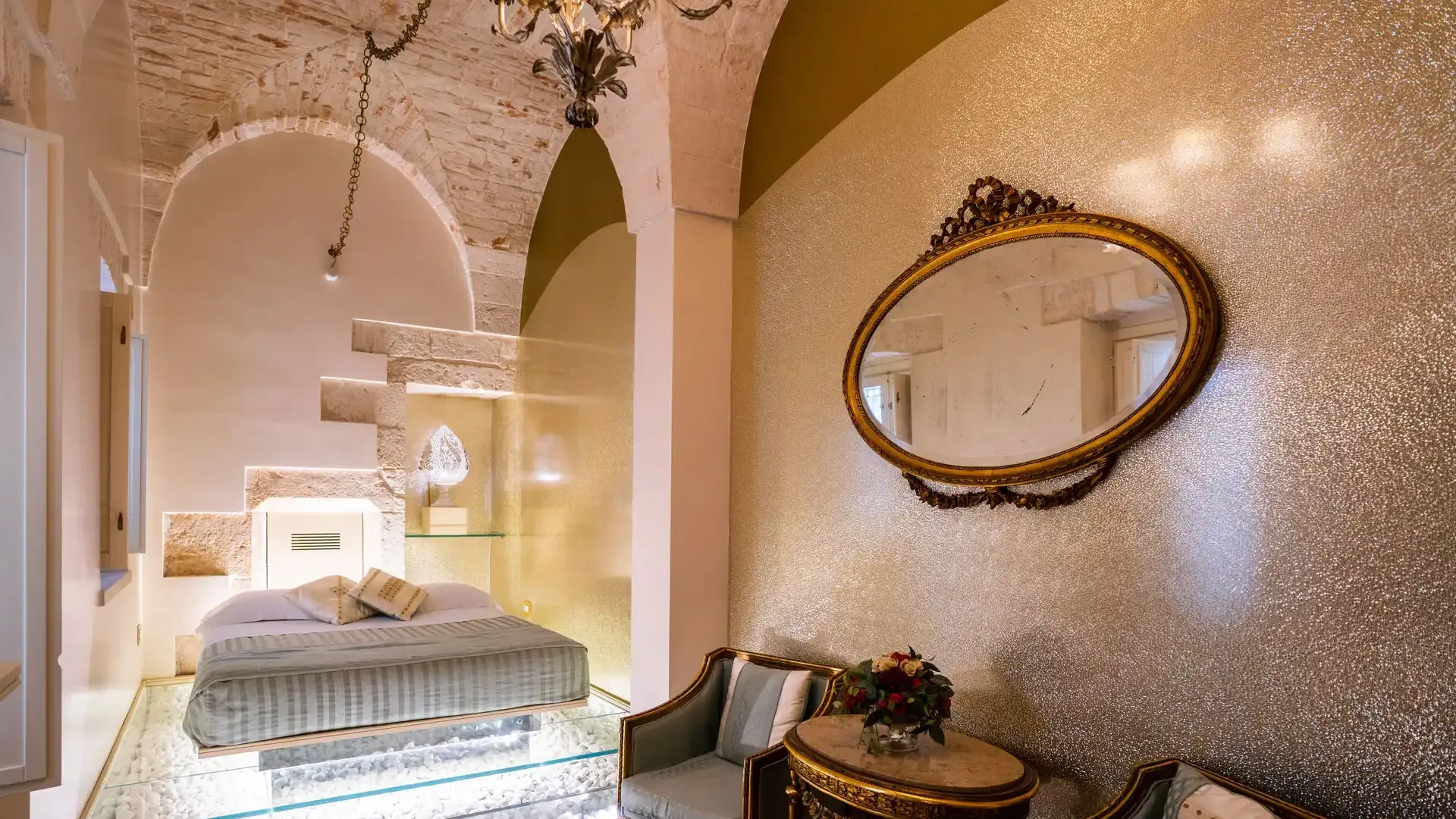 Elegant bedroom with vaulted ceiling and suspended bed over illuminated stones.