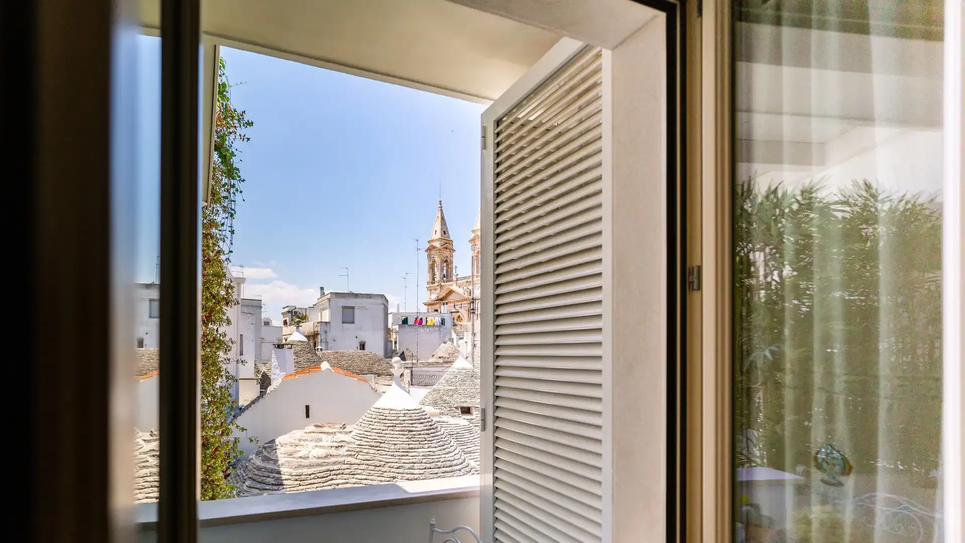 View of traditional rooftops and a church from an open window.
