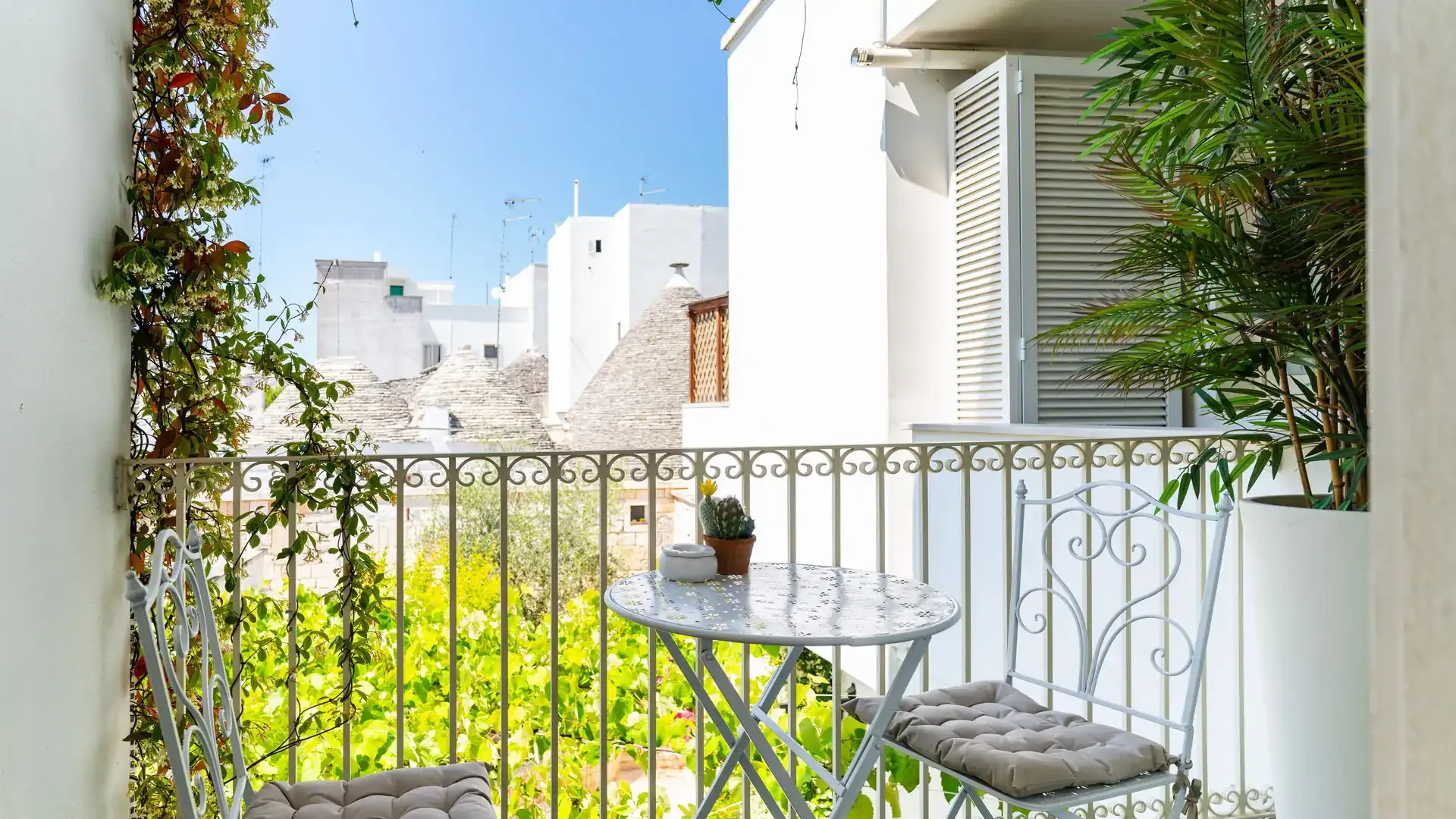 Cozy balcony with table, chairs, and rooftop view.