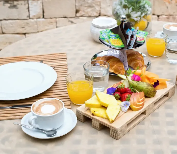 Breakfast with fruit, croissants, orange juice, and coffee.