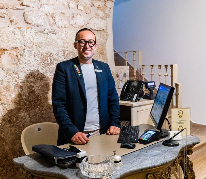 Réceptionniste souriant dans un bureau aux murs de pierre et mobilier élégant.