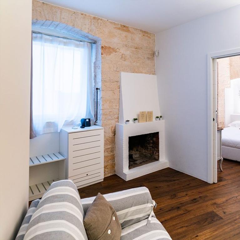 Accogliente soggiorno con camino, camera da letto luminosa e arredi rustici.