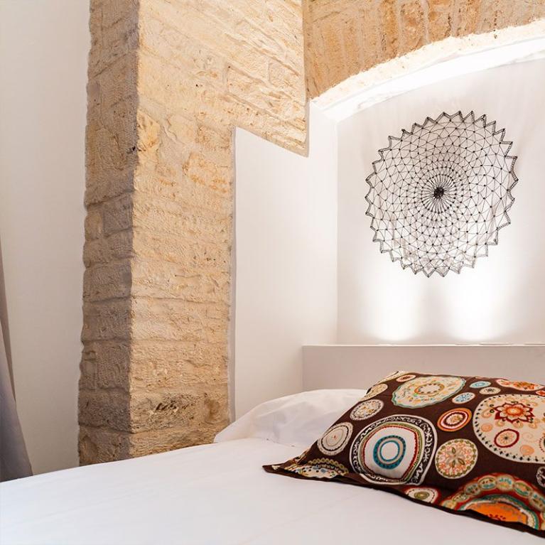 Camera da letto con cuscino colorato e decorazione geometrica sulla parete.