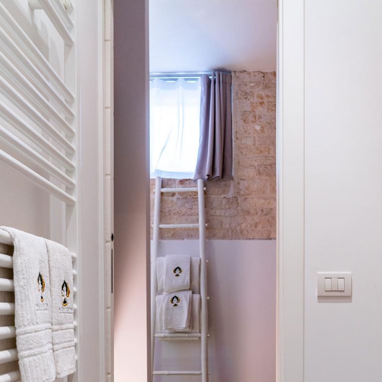 Bagno moderno con asciugamani bianchi, pareti in pietra e pavimento in legno.