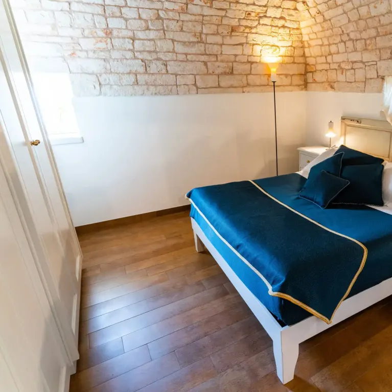 Camera da letto accogliente con letto matrimoniale e parete in pietra.