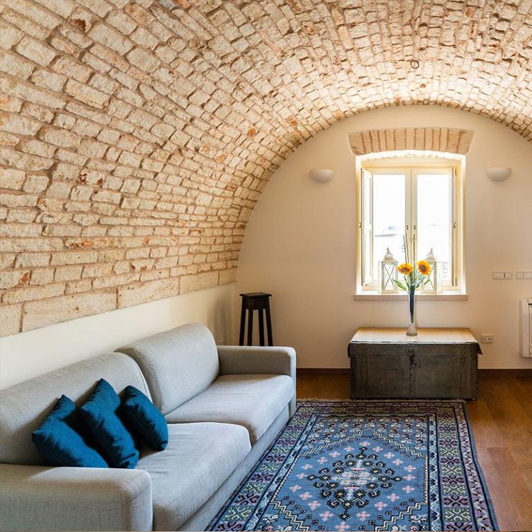 Accogliente soggiorno con soffitto a volta in mattoni e arredi eleganti.