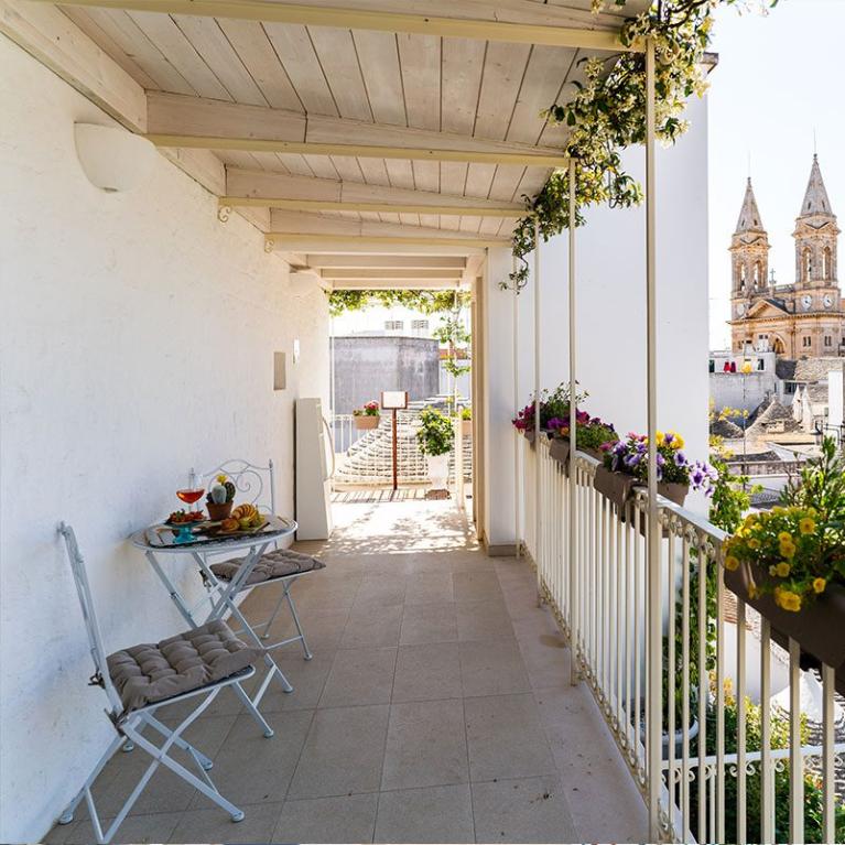 Balcone con vista sui trulli e una chiesa in lontananza.