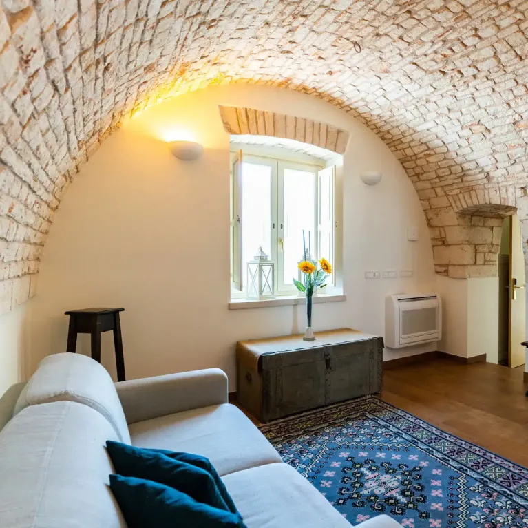 Accogliente soggiorno con soffitto a volta in mattoni e arredi moderni.