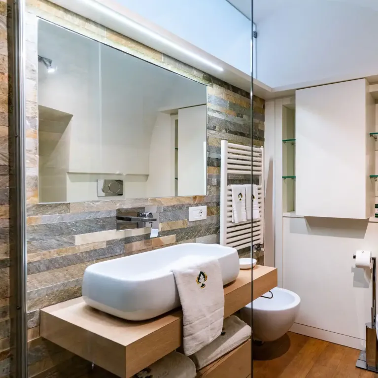 Bagno moderno con lavabo, bidet e WC, decorato con piastrelle e legno.